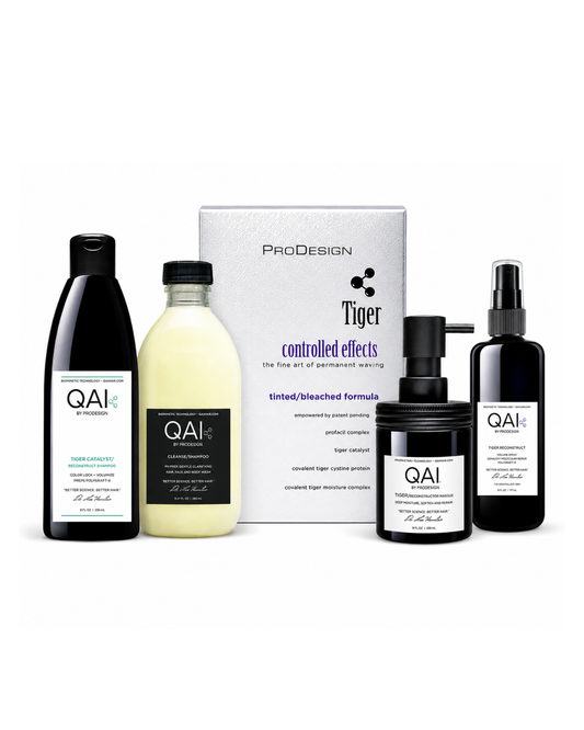 A hair color kit by QAI and ProDesign Tiger, featuring a black bottle of developer, a pale yellow bottle of developer, a black pump bottle of developer, a black spray bottle of developer, and a white product box, all arranged on a white background.